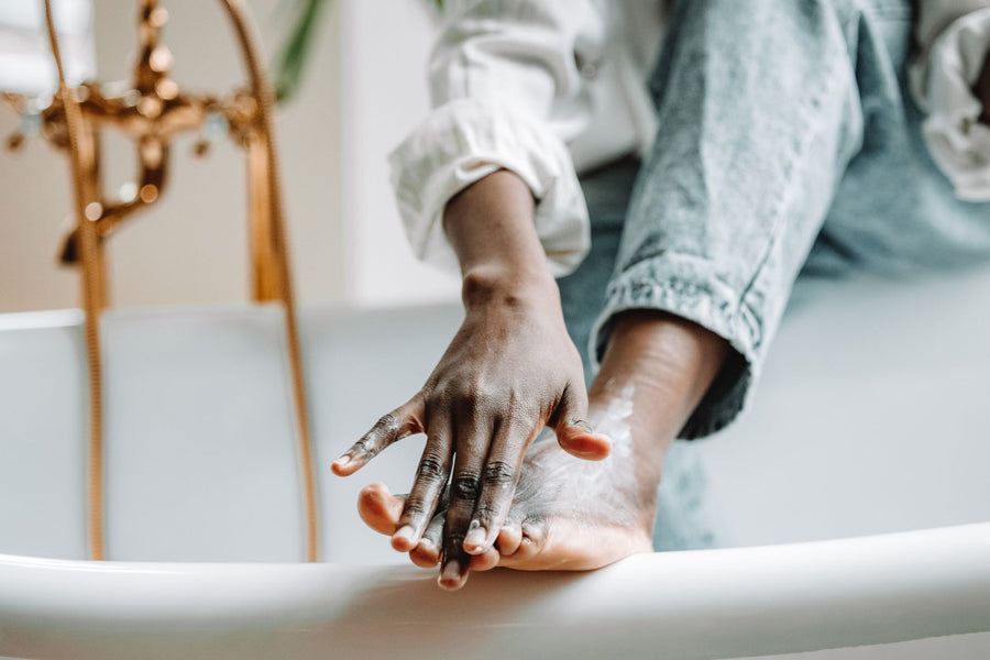 Applying cream to the foot while sitting on the edge of the tub