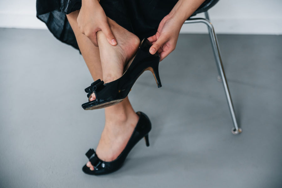 Woman slipping off her heels and rubbing her foot after work