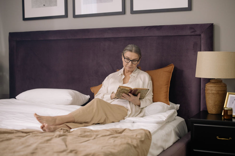 Woman reading in bed by lamplight before sleep